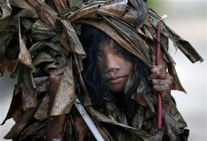 A muddied girl, donning a cape made of dried banana leaves, collects candles before attending a mass to celebrate the Feast Day of St. John the Baptist in the village of Bibiclat, Aliaga town, Nueva Ecija province in northern Philippines, Wednesday, June 24, 2015. AP Photo/Bullit Marquez